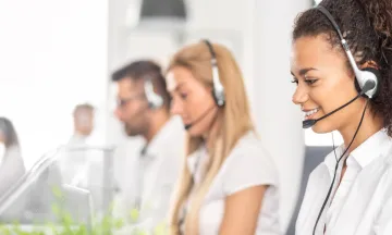 Stock image of customer service agents with headsets looking at computers