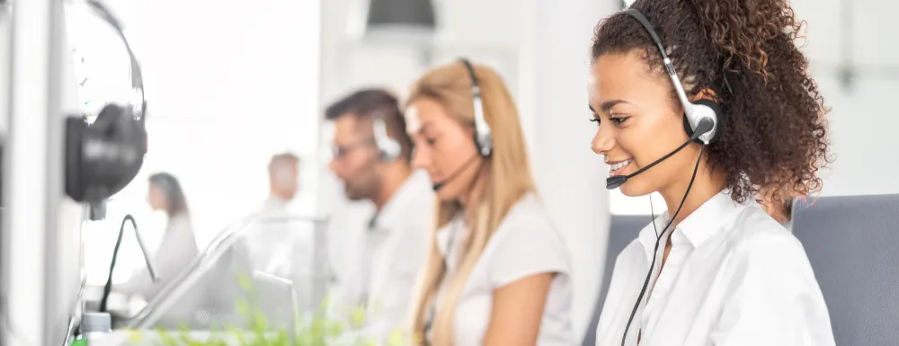 Stock image of customer service agents with headsets looking at computers