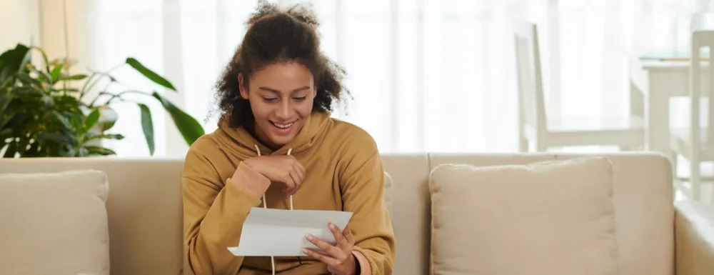 Young woman on a couch reading a piece of mail